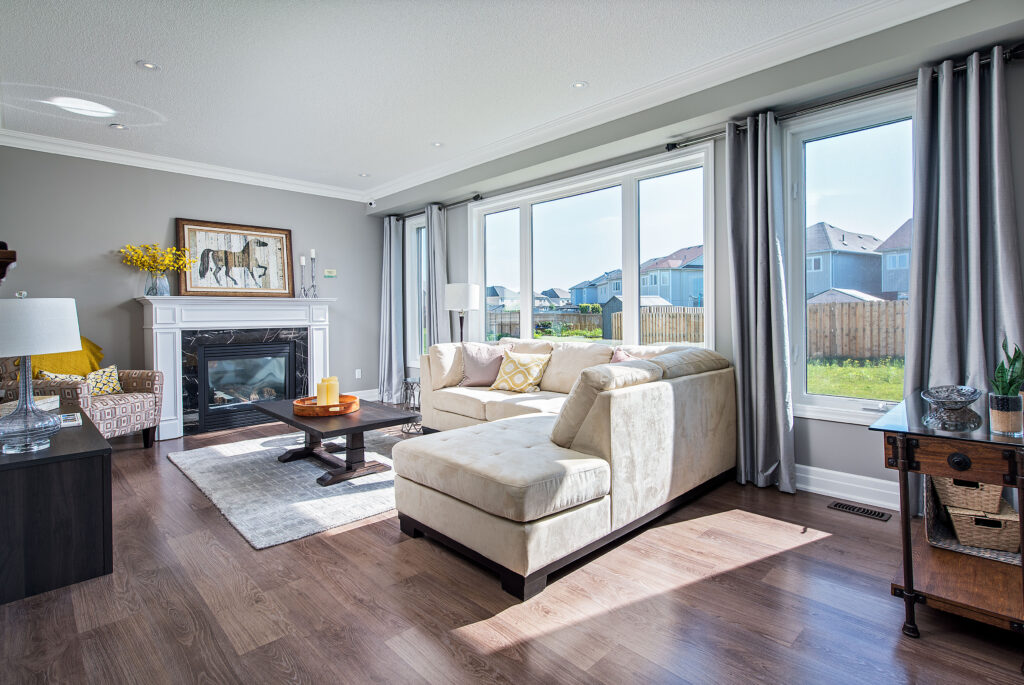 bright, sun-filled living room with large windows, fireplace and modern furniture, taken at Lancaster Homes' Pine River model home