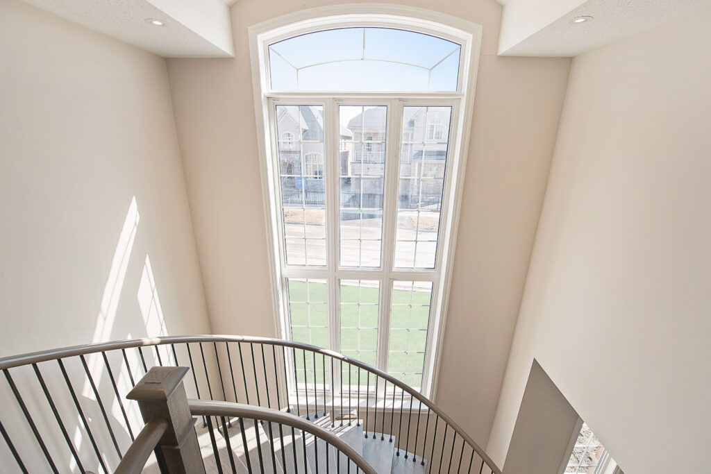 Very large vertical window with a spiral staircase in front, from Lancaster Homes' Simcoe Landing community