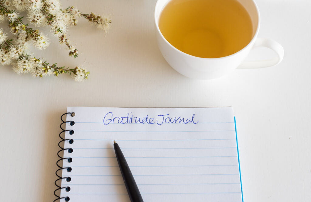 gratitude journal, flowers and a pleasant cup of tea